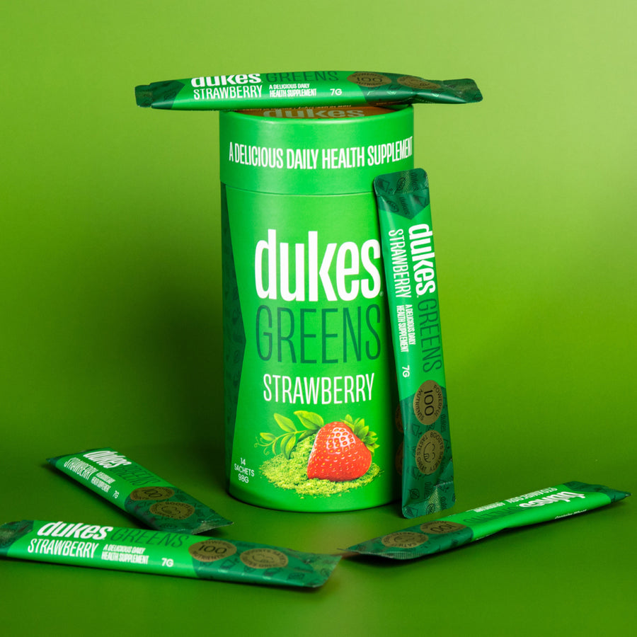 98g 14 Sachet Tube of Dukes Green Health Supplement Strawberry Flavour on a green background with sachets placed around it.