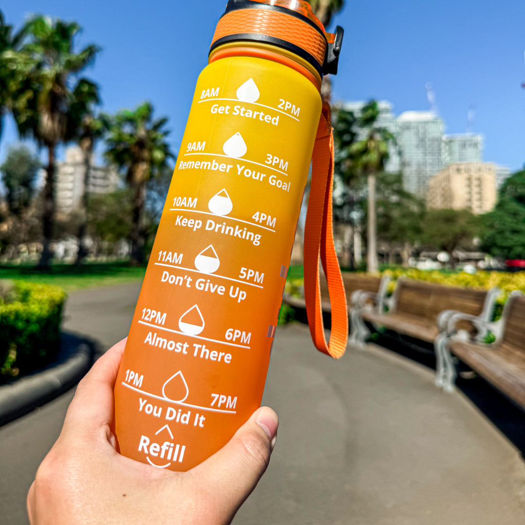 A close-up Dukes motivational bottle being held up with a blurred city park scene in the background.
